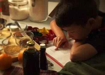 Close-up of boy reading cookbook at kitchen