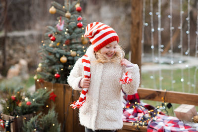 Funny cheerful kid girl 4-5 year old wear red knitted scarf and hat with coat playing