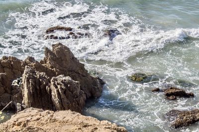 High angle view of waves splashing on rocks at shore