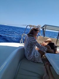 Man and woman sitting in boat on sea against clear sky