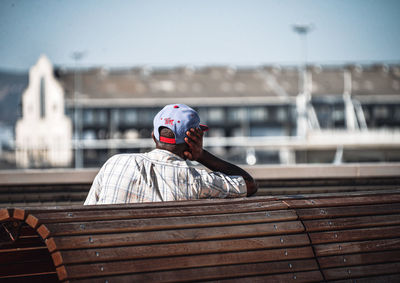 Portrait of man sitting on railing against sky