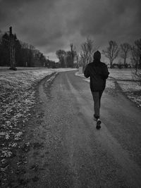 Full length rear view of man walking on road
