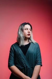 Portrait of beautiful young woman against red background