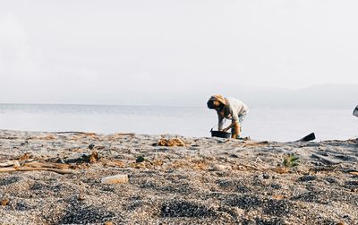 Man on rock at beach against sky