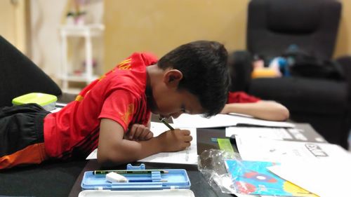 Boy drawing on book in classroom