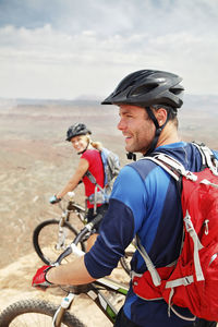 Happy couple standing with bicycles on cliff