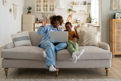 African american mother and kid son looks at web camera laptop for video call at home. happy family