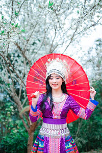 Portrait of a smiling woman standing against trees