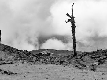 Cross on land against cloudy sky
