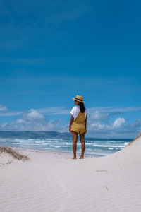 Full length of woman standing at beach against sky