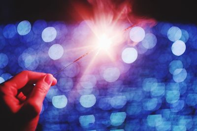 Close-up of human hand holding illuminated sparkler at night