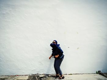 Full length of woman standing against wall