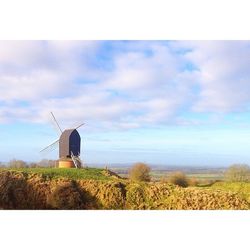 Traditional windmill on field against sky