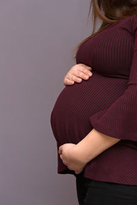 Midsection of woman standing against gray background