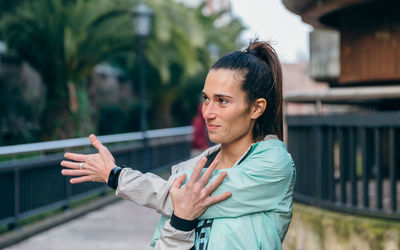 Brunette woman runner stretching her arm before training outside