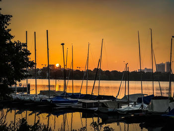 Sailboats moored at harbor during sunset