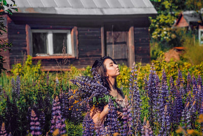 Woman standing in front of flowering plants in yard