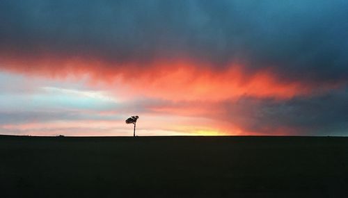 Scenic view of silhouette field against sky during sunset