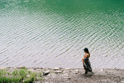 Full length rear view of woman standing on sea shore