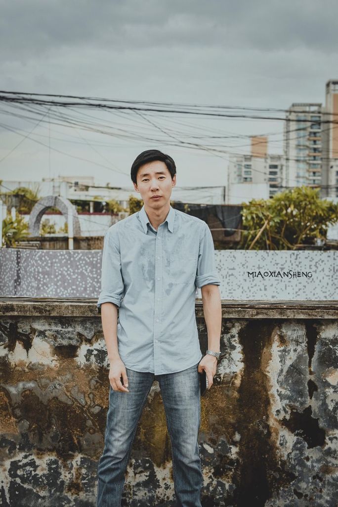 casual clothing, lifestyles, looking at camera, standing, portrait, person, young adult, built structure, building exterior, architecture, front view, young men, leisure activity, three quarter length, railroad track, sky, jacket, day