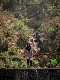 Woman standing by tree in forest