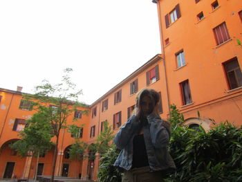 Woman standing by building against clear sky