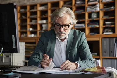 Male design professional choosing fabric from swatch at desk in office