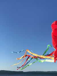 Low angle view of kites against clear blue sky