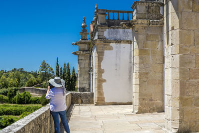 Rear view of woman standing at historic building against sky