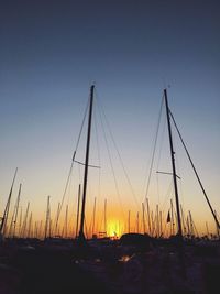 Sailboats moored in sea against clear sky during sunset