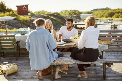 Young multi-ethnic friends enjoying summer lunch at harbor