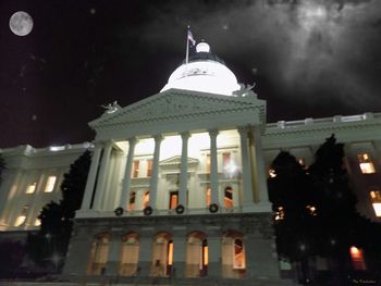 Low angle view of statue in city against sky at night