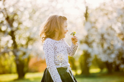 Cute girl smelling flower while standing at park
