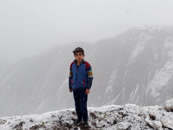 Portrait of boy standing on snowcapped mountain