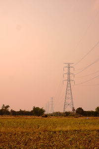 Electricity pylon on field against sky during sunset