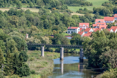 Bridge over river amidst trees and buildings