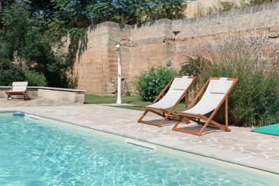 Swim pool with clear blue water and two sun bed on sunny day in a yard, beautiful vacation 