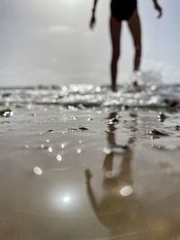 Low section of woman walking in sea during sunny day