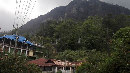 Houses by trees and mountains against sky