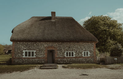 Old house amidst trees and buildings against sky