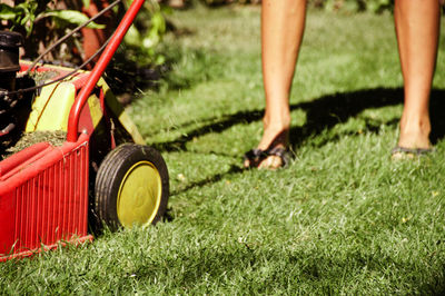 Low section of woman with lawn mower on field