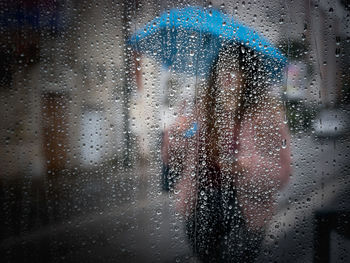 Woman seen through wet glass window in rainy season