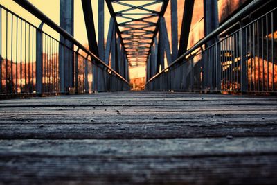 Surface level of bridge against sky at sunset