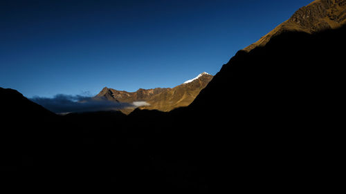 Silhouette of mountain range against blue sky
