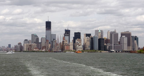 Sea by modern buildings against sky in city