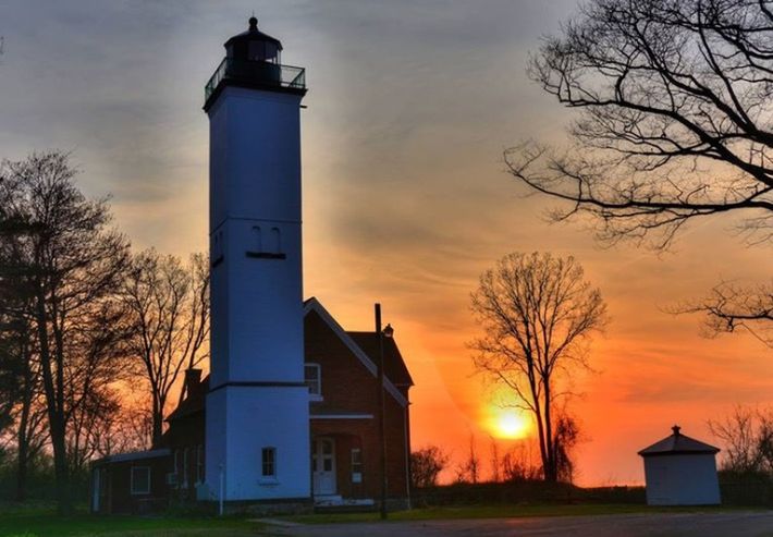 architecture, sunset, building exterior, built structure, sky, bare tree, orange color, cloud - sky, tree, lighthouse, guidance, house, tower, low angle view, cloud, no people, silhouette, sunlight, outdoors, sun