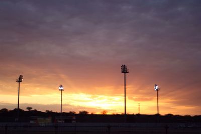 Low angle view of silhouette street lights against sky during sunset