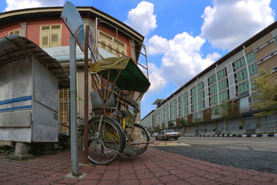 Bicycles on street by buildings in city against sky