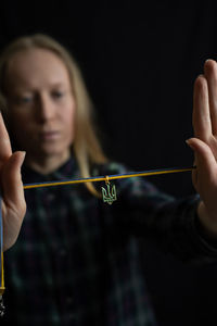 Portrait of young woman blowing bubbles against black background