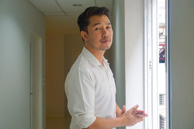 Portrait of young man standing against door